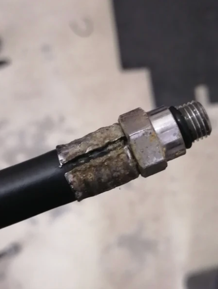 Cracked rubber sleeve on a worn scuba hose at the banjo fitting